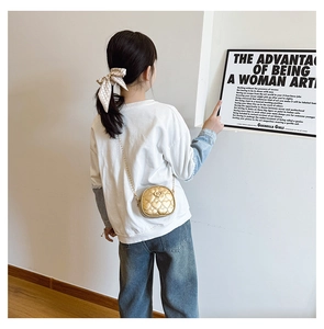 Mini sac bandoulière doré matelassé en cœur pour fille porté par un mannequin