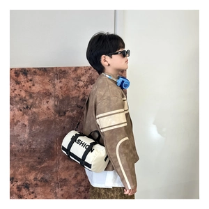 Détail d'un enfant portant un sac bandoulière cylindrique blanc cassé avec imprimé