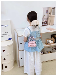 Detailed view of pink bow handbag with fine metal chain strap and PU leather texture