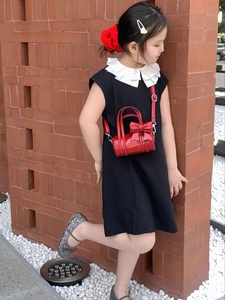 Detail of red cylinder mini bag for girls with large bow and shiny metallic finish