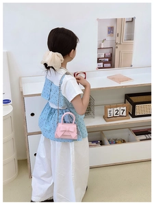 Close-up of pink girls' bow handbag featuring a metallic chain strap on child model