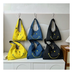 Detailed view of canvas tote bags with smile embroidery in yellow, blue and black colors