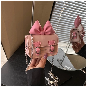 Détail du mini sac rose avec grand nœud, boucles en cœur et fine chaîne argentée