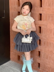 Girl's white cylindrical leather handbag with bow paired with swan print t-shirt and tutu