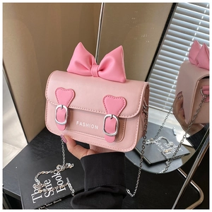 Détail du sac bandoulière rose à nœud avec boucles en cœur et bandoulière chaîne