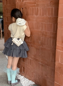 Outdoor shot of a girl wearing a white bow cylinder bag with a layered tutu skirt