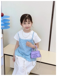 Detail view of purple mini handbag with a large bow held by a child model in a studio