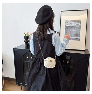 Fillette portant un petit sac à bandoulière matelassé cœur blanc avec chaîne dorée