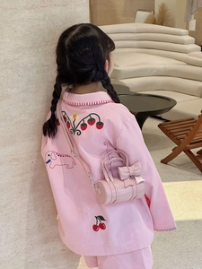 Close-up of pink children pajama with strawberry embroidery and matching bow handbag