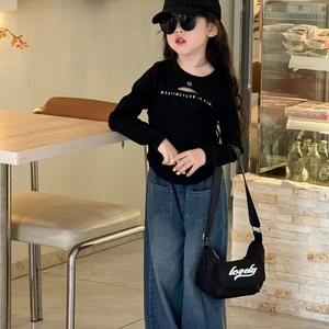 Child in casual black letter T-shirt, wide jeans, and a stylish black crossbody bag