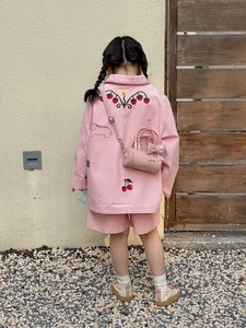 Detail of pink bow cylinder handbag paired with cute embroidered jacket and shorts for girls