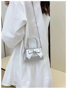 Silver bow mini handbag with chain strap shown on model in white dress for kids