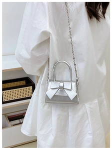 Detail of silver mini crossbody bag with a large bow and metallic chain strap