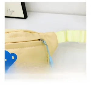 Detail of baby chest bag showing light yellow twill fabric and blue bear print with zipper