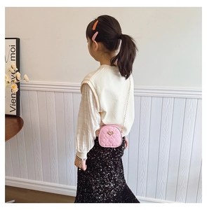 Détail d'une boucle en forme de cœur sur un sac à bandoulière matelassé rose pour filles
