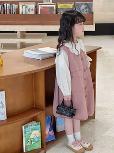 Detail of girls' pink corduroy dress with white lace collar and black mini handbag