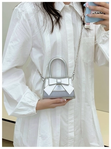 Detailed view of a silver mini bag featuring a large bow and metallic chain strap