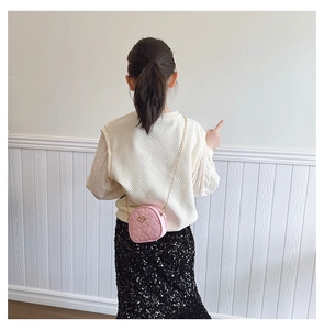 Sac matelassé rose en forme de cœur avec détails dorés porté par un enfant
