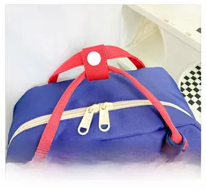 Détail de la poignée en sangle rouge et de la fermeture éclair ivoire du sac à dos enfant