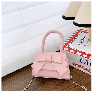 Close-up of pink mini PU leather handbag featuring a large bow and gold chain strap