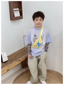 Detail of yellow kids chest bag with blue bear print worn across the chest on a child