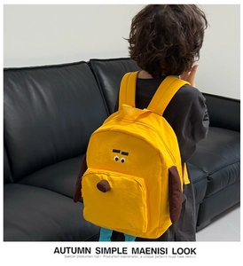 Dettaglio di uno zainetto giallo a forma di cane per bambini indossato da un piccolo modello