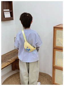 Back view of a child wearing a bright yellow cartoon bear chest bag in a cozy home setting