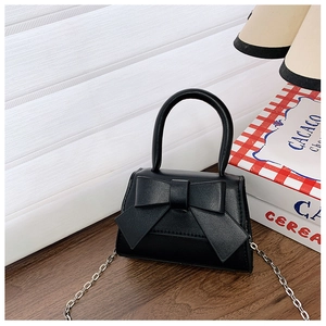 Close-up of black mini handbag featuring a large bow and a sleek silver metal chain