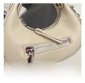 Detail of off-white crescent bag featuring pebble grain leather and silver metal zipper