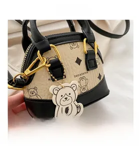 Detail view of mini teddy bear print shell bag with golden zipper and leather charm