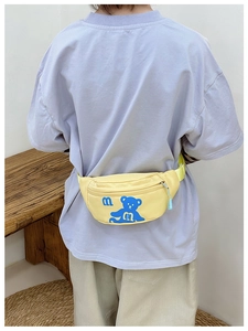Detailed view of yellow waist bag with blue bear print worn by a child in a home setting