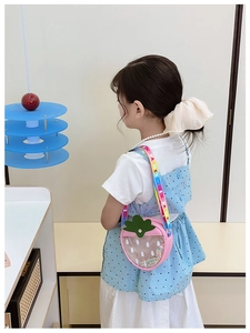 Detail of pink strawberry kids bag featuring transparent layer with sequins and rainbow strap