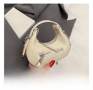 Detailed macro view of off-white lychee grain leather handbag with decorative zipper
