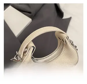 Detail shot of the textured cream leather handle and silver metal zipper on the handbag