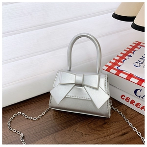 Close-up of silver metallic girl handbag with large bow and elegant chain strap