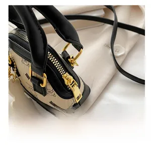 Close-up of smooth gold zipper and hardware on cream mini shell bag with bear print