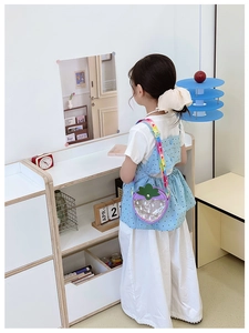 Girl wearing a strawberry-shaped purple crossbody bag with colorful sequins and strap