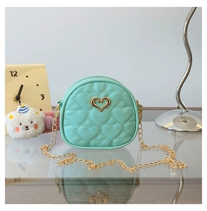 Détail du mini sac vert menthe avec matelassage en cœur, chaîne d'or et boucle cœur