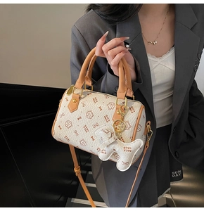 Detailed view of cream Boston bag featuring cat print patterns and bone-shaped charm