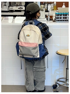 Detailed back view of a color-block school backpack on a child model with large capacity