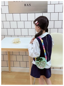 Close-up of strawberry-shaped sequin bag with rainbow strap worn by child model