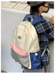 Detail of color-block school backpack showing side pocket and mountain logo patch