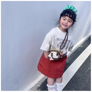 Detailed view of child's brown shell-shaped crossbody bag with cute white bear charm