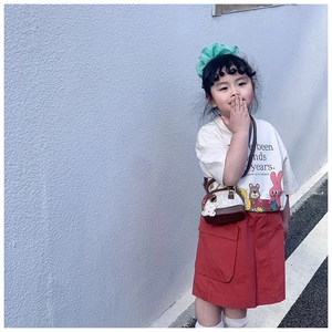 Close-up of a mini cylinder crossbody bag with bear charm and chic kids outfit details