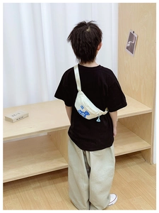 Detailed view of cream nylon waist bag with a cartoon bear print for children on a model