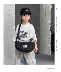 Sac bandoulière noir pour enfants avec lettrage sport blanc porté en style urbain chic