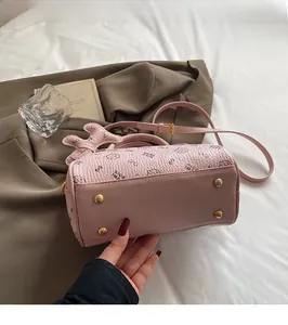 Detailed view of pink lychee leather handbag with cat prints and metal bottom studs