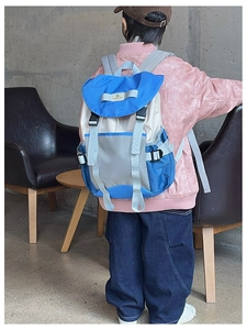 Rear view of child wearing a multi-color drawstring backpack with buckle flap and side mesh pocket