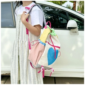 Detail view of colorful patchwork backpack with heart pattern and drawstring on model