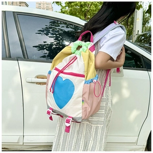 Detailed view of colorful heart backpack with drawstrings shown on a model outdoors